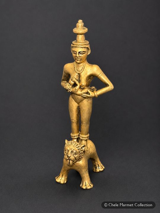 Tall gold-coloured figure of a woman nursing a child, standing on the back of a lion.