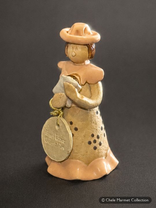 Small unglazed clay figure of a woman in a wide-brimmed hat holding a baby.