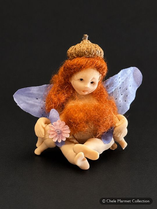 Small figure of a red-haired fairy with lavender wings and a flower crown, nursing two babies.