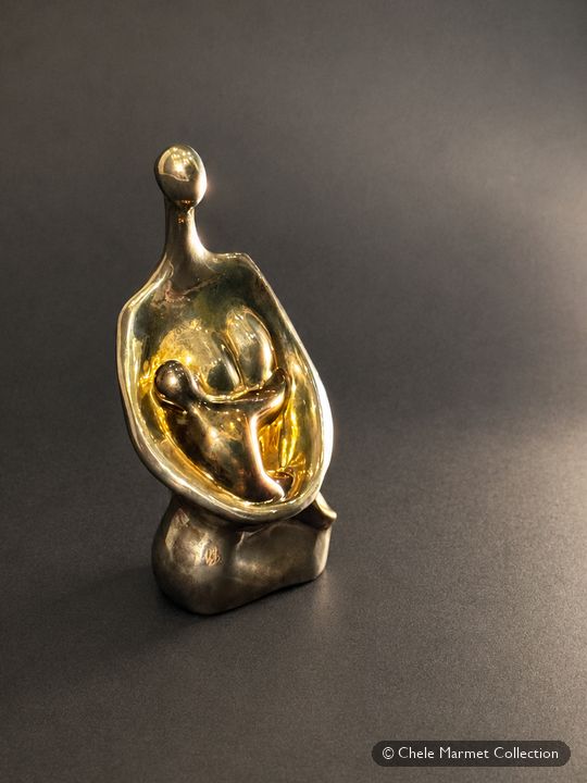 Small polished bronze-coloured abstract sculpture of a mother curved around a baby.