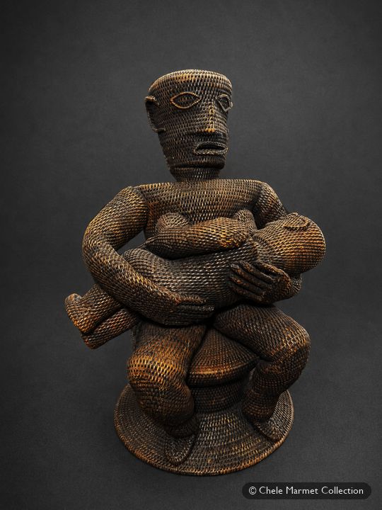 Woven brown figure of a seated mother nursing a baby.