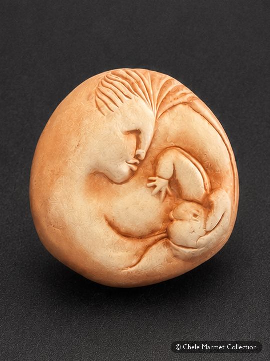 Smooth round peach-coloured clay piece shaped as a mother curled around a baby.