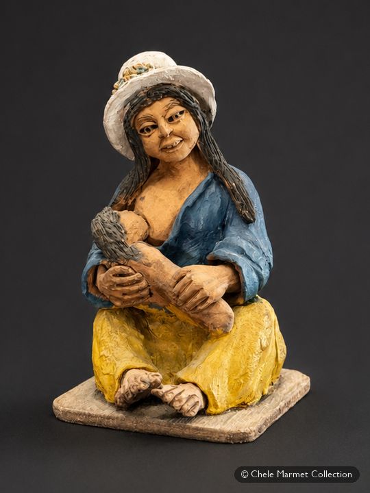 Painted figure of a seated woman in a white hat and blue shawl, nursing a baby.