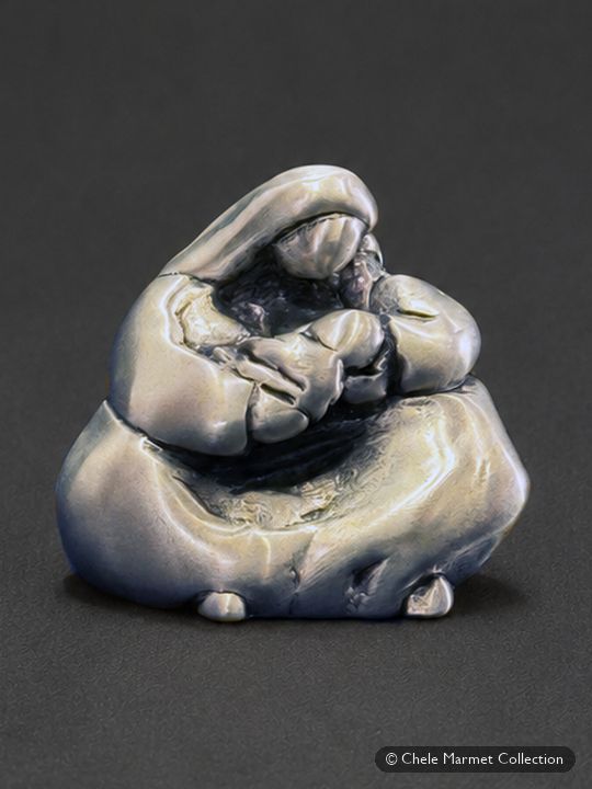 Tiny silver-coloured metal figure of a seated, shawled mother holding a baby.
