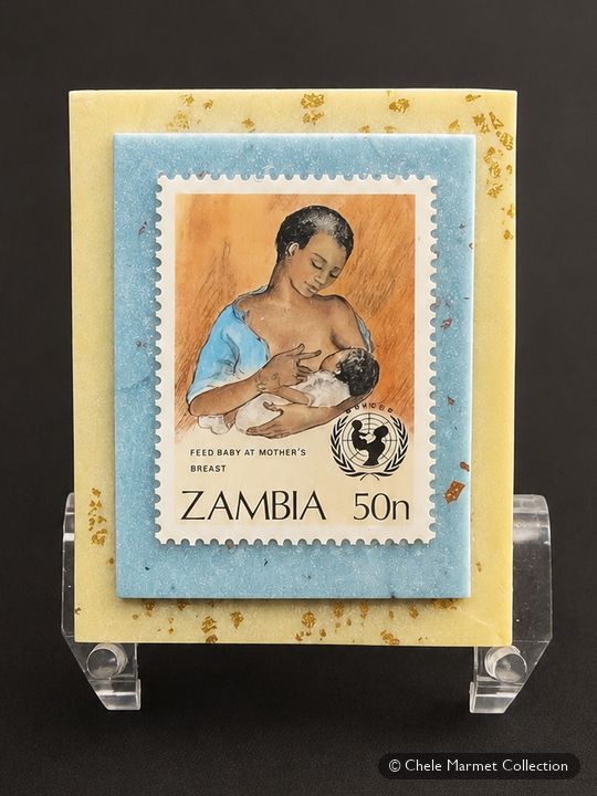 Zambian stamp bearing the UNICEF emblem, showing a mother nursing a baby, mounted on a blue and yellow card.