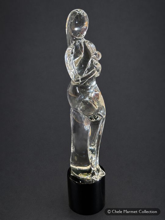 Clear glass sculpture of a mother holding a baby on a black base.