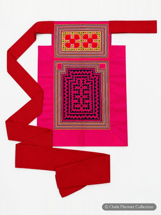Pink apron with a panel of red, purple and yellow geometric embroidery and long red ties.